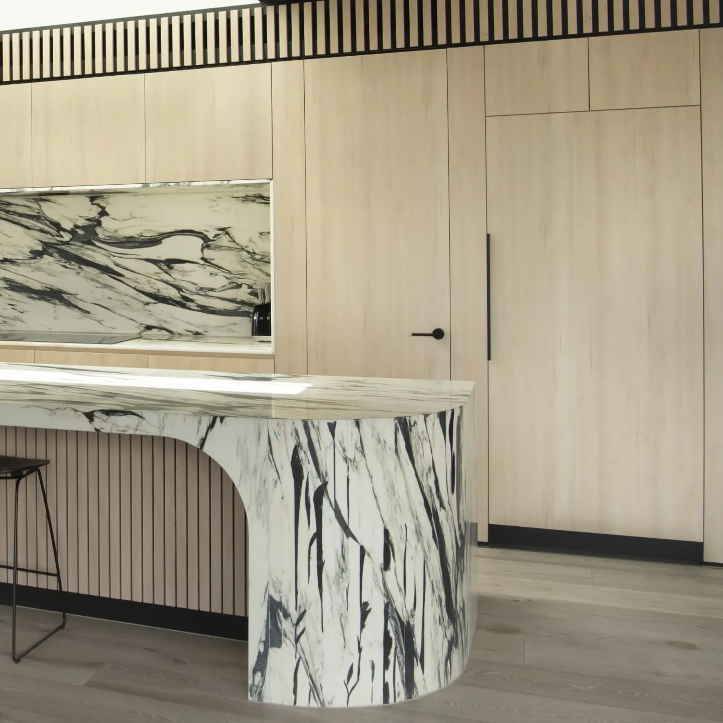 Curved marble island end detail with matching splashback and timber cabinetry, Pascon build, South Melbourne.