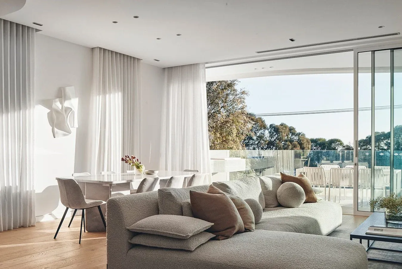 All-white open-plan living and dining room with floor-to-ceiling glazing and terrace views, built by Pascon.