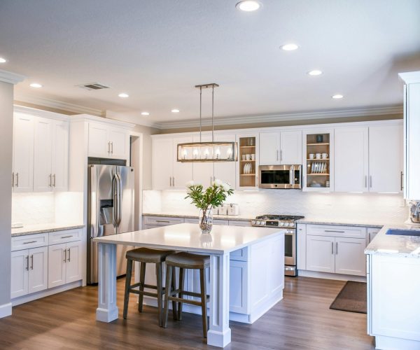 Elegant white kitchen featuring an island, modern appliances, and ample natural light.
